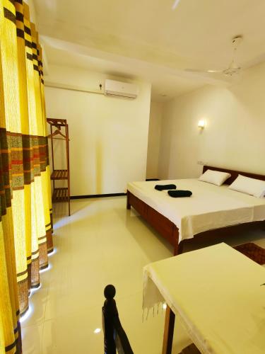 a room with two beds and a table in it at Randi Guest Mirissa in Mirissa