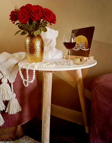 a table with a vase of roses and a glass of wine at Laci Lak Premium apartment in Oradea