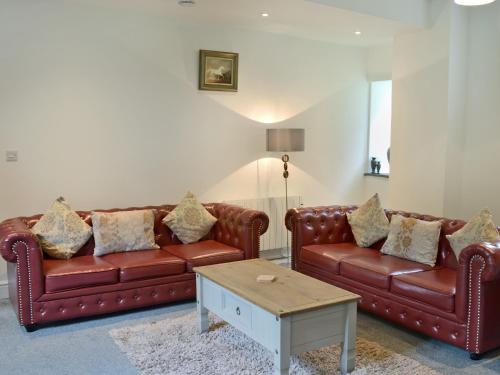 a living room with two leather couches and a coffee table at Rosecraddoc Manor - Stable in Saint Cleer