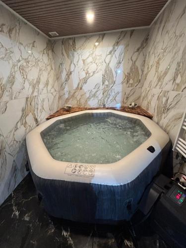 a jacuzzi tub in a bathroom with marble walls at Maison Relax Spa & tranquillité in Auberchicourt