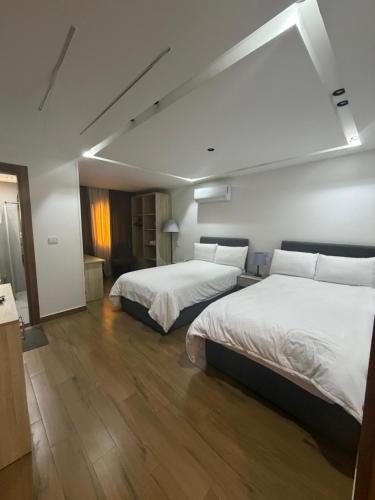 two beds in a hotel room with white sheets at الحصرى Elhosary otel in 6th Of October