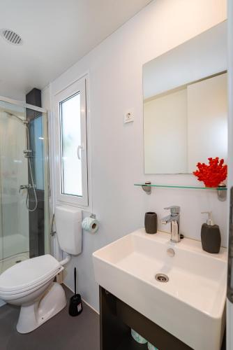 a bathroom with a sink and a toilet and a mirror at House no 3 in Pakoštane