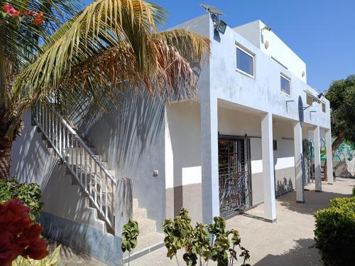 een wit huis met een trap en een palmboom bij Guorgui's bed in Ndangane