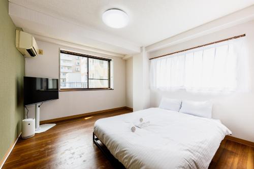 a bedroom with a white bed and a window at なな宿 浅草三ノ輪 in Tokyo