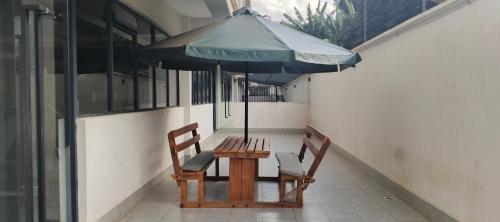 a wooden table and two chairs under an umbrella at Fun-fantastic Furnished Apartment, The Loftel near UN, Embassies, Two Rivers & Village Market,with a Pool and Gym in Nairobi