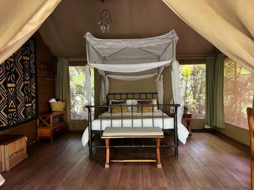 a bedroom with a canopy bed in a tent at Ikweta Safari Camp in Kinna