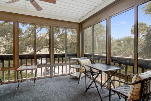 a screened in porch with a table and chairs and windows at Spinnaker 716 in Seabrook Island