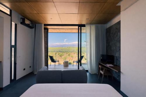 a bedroom with a bed and a couch and a window at Boutique Hotel Bodega CICLO ANDINO in Perdriel