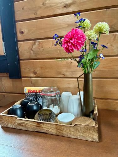 a wooden tray with a vase with flowers in it at Landelijk gelegen houten huisje in Opperdoes