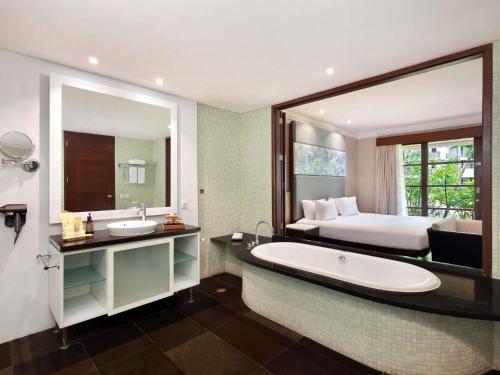 a bathroom with a large mirror and a bed and a tub at Novotel Bali Nusa Dua in Nusa Dua