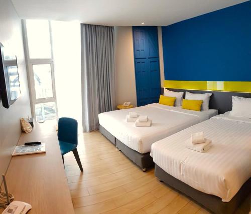 a hotel room with two beds and a blue wall at Hotel Tranz in Bangkok