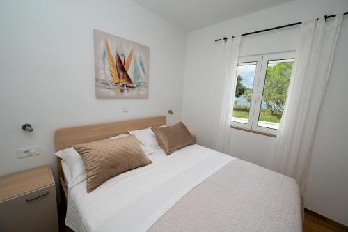 a bedroom with a white bed and a window at Beachfront house Miamore - 10 m from the sea in Pašman