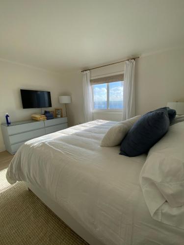 a bedroom with a large white bed with a window at Pearl on the Point in Carolina Beach