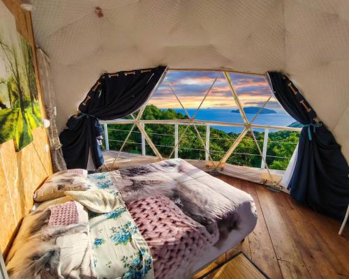 a bed in a room with a large window at Agriturismo Glamping Erbe Matte in SantʼAntìoco