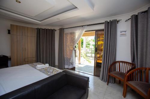 a bedroom with a bed and a couch and a window at Lorateng' Resort - Rusinga in Mbita