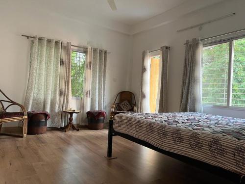 a bedroom with a bed and two windows at Pappu niwas in Siliguri