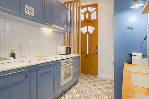a kitchen with blue cabinets and a sink and a door at Selah Residence in Oradea