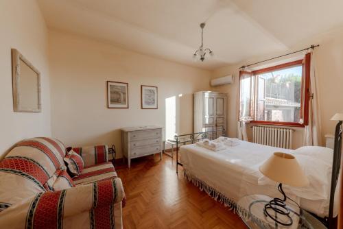 a bedroom with a bed and a couch and a window at Holiday House Borgo Badia in Castiglione del Lago