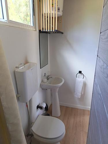 a white bathroom with a toilet and a sink at Cabaña Esencia in Maldonado