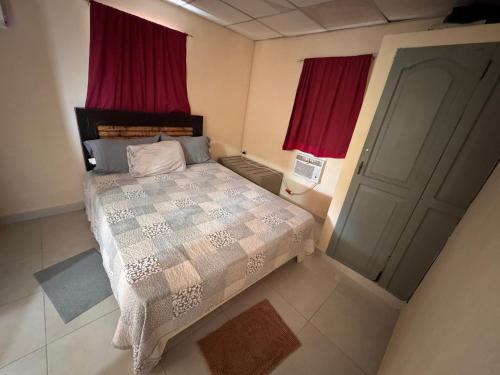 a bedroom with a bed with red curtains and a door at Casa de campo El Bonao in Higuey