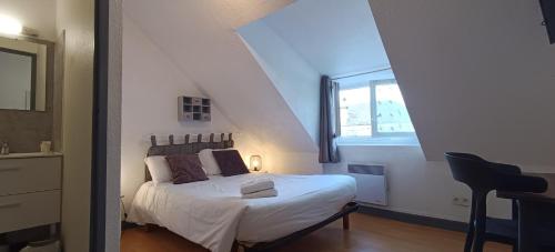 a bedroom with a white bed with a window at Hôtel Le P'tit Monde in Montignac