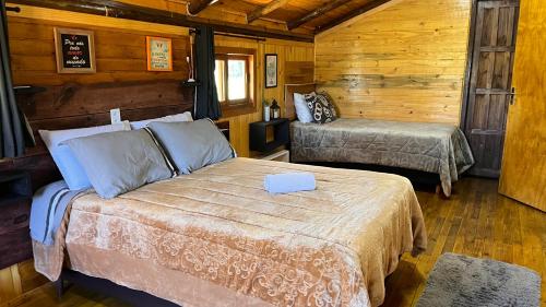 a bedroom with two beds in a wooden cabin at Morada das Estrelas in Cambará