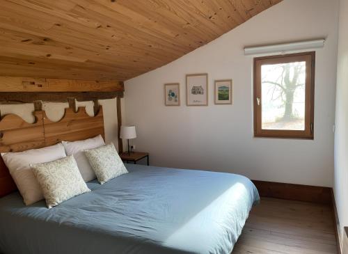 a bedroom with a blue bed with a wooden ceiling at Domaine Bourgade in Betbezer