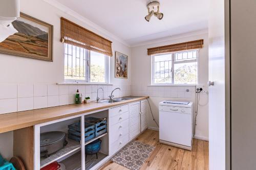 a kitchen with white cabinets and a sink at The Mermaid's Tail in Pringle Bay