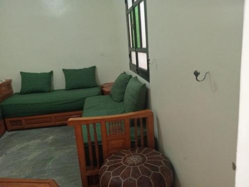 a living room with a green couch and a window at Dar Tissila in Marrakesh