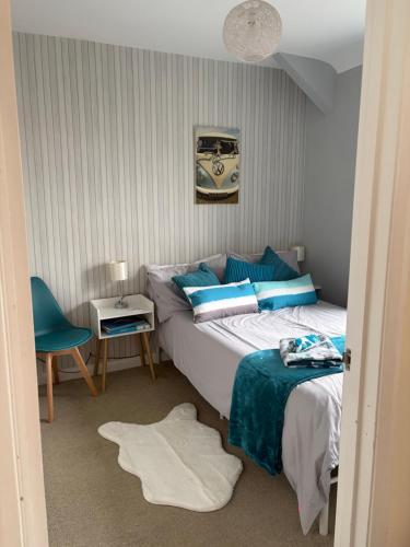 a bedroom with a bed and a blue chair at Roseus and Mimosa Cottages in Combe Martin