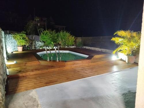 a pool with a wooden deck with a water fountain at Location Saisonnière Les Caféiers in Le Tampon