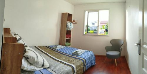 a small bedroom with a bed and a window at Location Saisonnière Les Caféiers in Le Tampon