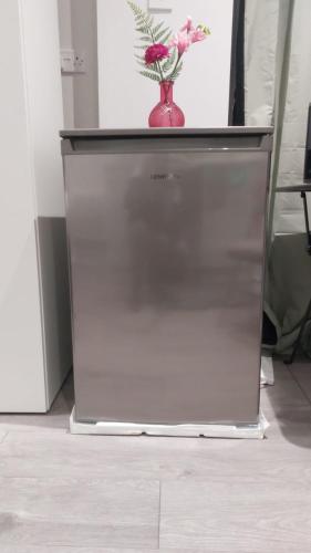 a refrigerator with a vase on top of it at Serene and Cosy Private Studio in Milton Keynes
