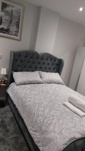 a bedroom with a large bed with a padded headboard at Serene and Cosy Private Studio in Milton Keynes