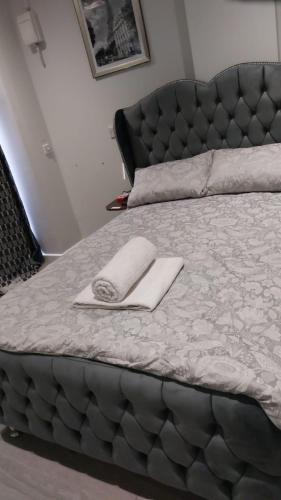 a bed with a black headboard and a white towel on it at Serene and Cosy Private Studio in Milton Keynes