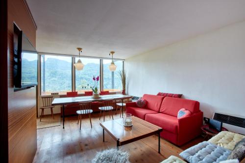 a living room with a red couch and a table at Modernist Chalet in Borca di Cadore