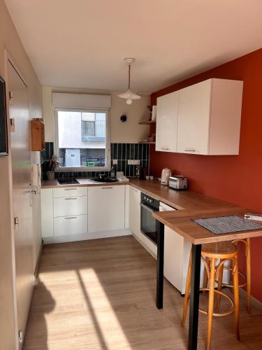 Duplex proche centre ville في رين: مطبخ بخزائن بيضاء وطاولة خشبية