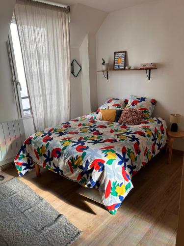 Duplex proche centre ville في رين: سرير مزين بغطاء ملون في غرفة نوم