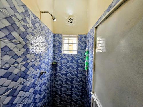 a bathroom with a blue tiled shower with a window at Deripacs Homes in Lodwar