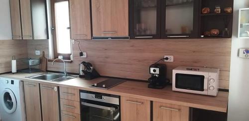 eine Küche mit Holzschränken, Mikrowelle und Spüle in der Unterkunft Къща Амфора in Trjawna