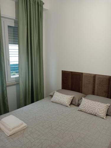 ein Schlafzimmer mit einem Bett mit zwei Kissen und einem Fenster in der Unterkunft Dimora Cristella in Eboli