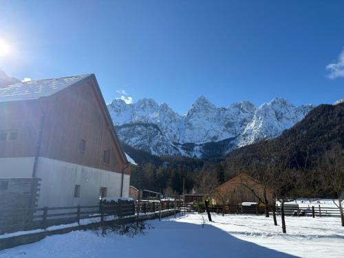 a barn in the snow with mountains in the background at Apartment Barbara with sauna in Gozd Martuljek