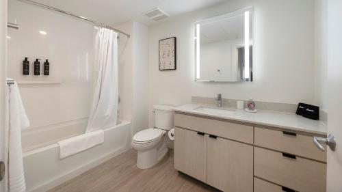 a white bathroom with a toilet and a tub and a sink at Landing Chic 2BD Gym Clubhouse in Tempe