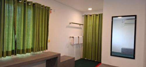 a bathroom with green shower curtains and a mirror at Bhagya Resort Limited in Nikawatawana