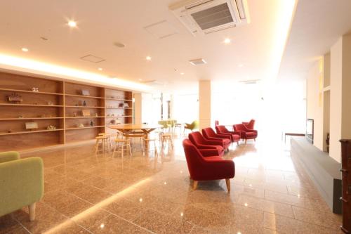 a waiting room with red chairs and a table at Amakusa Santacoming Hotel in Amakusa