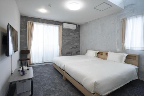 a bedroom with a large white bed and a desk at Laon Inn Plus Miyakojima in Miyako-jima