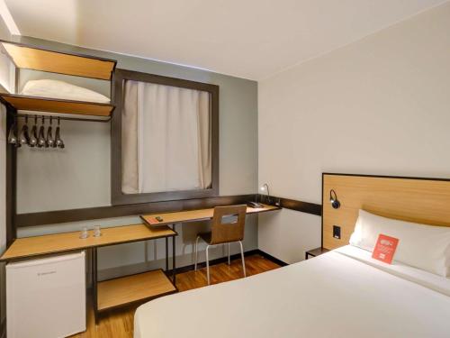 a hotel room with a bed and a desk and a bed sidx sidx sidx sidx at ibis Vitoria Praia de Camburi in Vitória