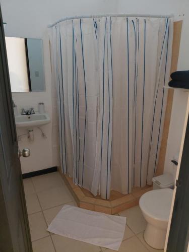 a bathroom with a shower curtain and a toilet at Sunset House Herradura in Herradura