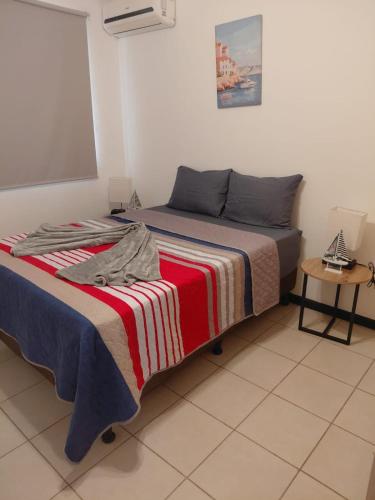 a bedroom with a bed with a striped blanket at Sunset House Herradura in Herradura
