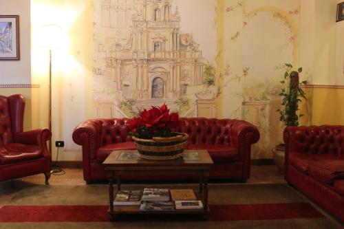 a living room with two red couches and a table at Hotel Il Barocco in Ragusa